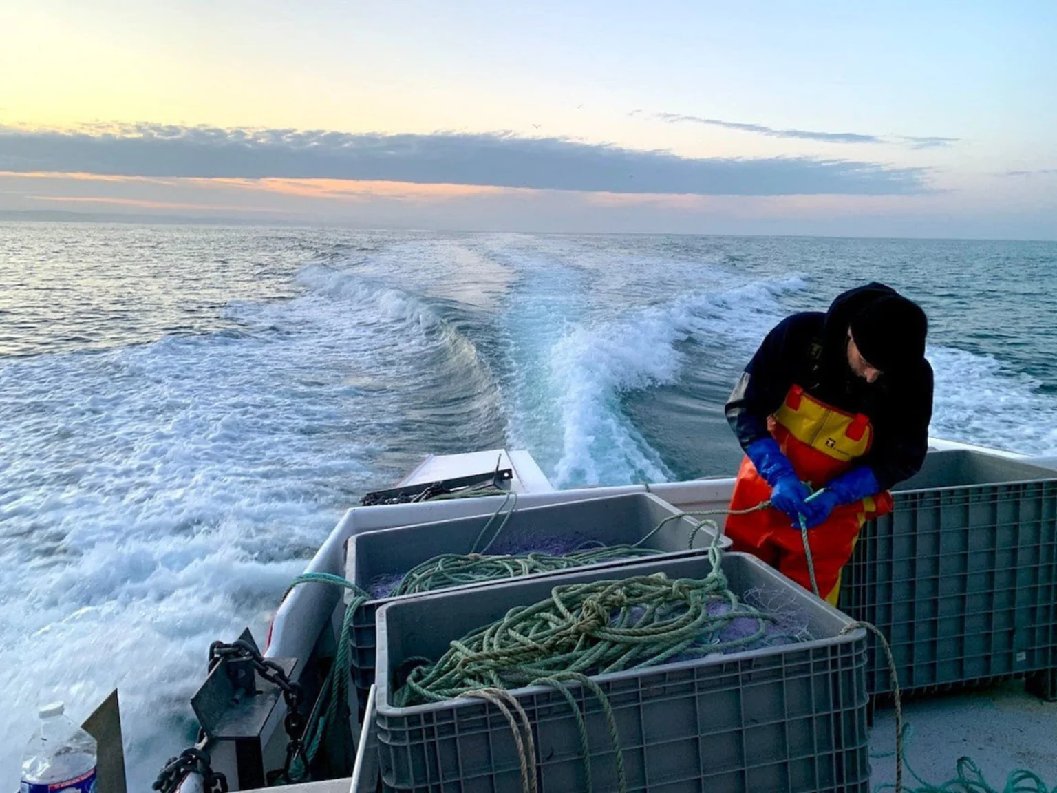 Photo de pecheur qui range ses filets à bord