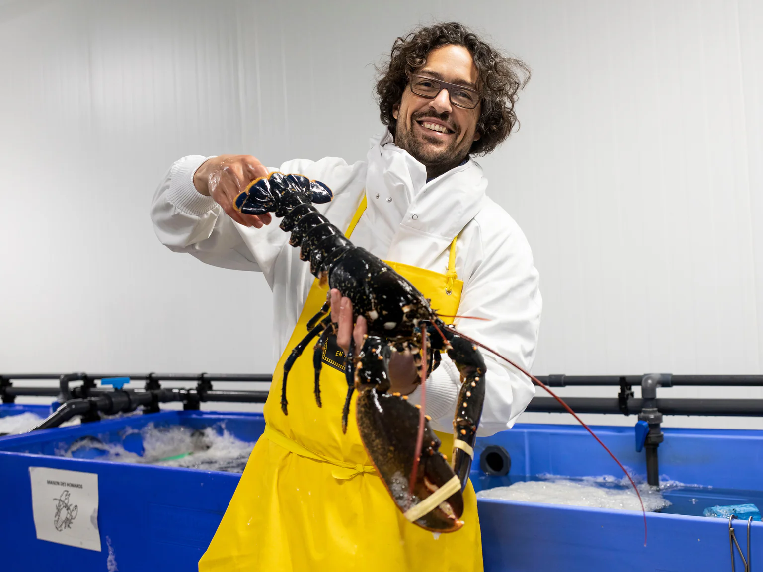 Charles Guirriec, fondateur de Poiscaille brandissant un homard bleu breton