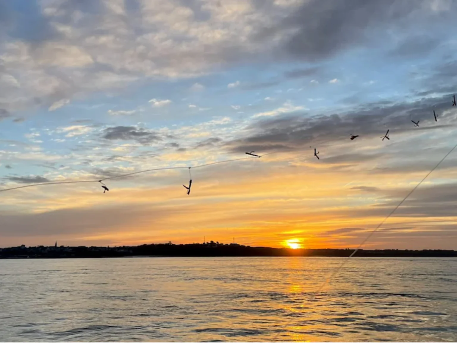 Un lever de soleil sur la rade de Brest, avec la ligne à maquereau qui part à l'eau.